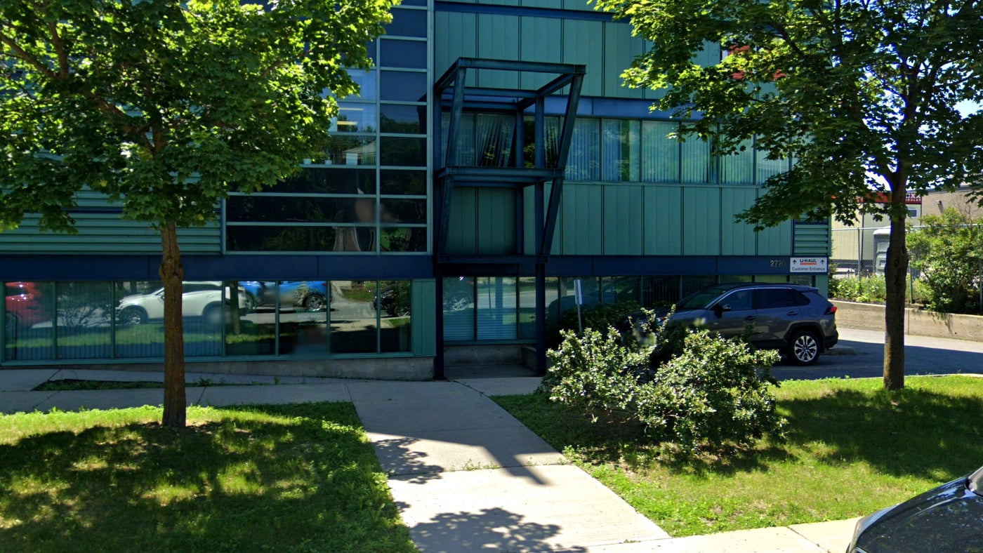 The entrance to the store: a recessed glass door under a black steel frame, on the Queensview Drive side of the building